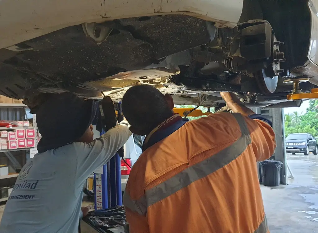 Mechanic inspecting vehicle undercarriage